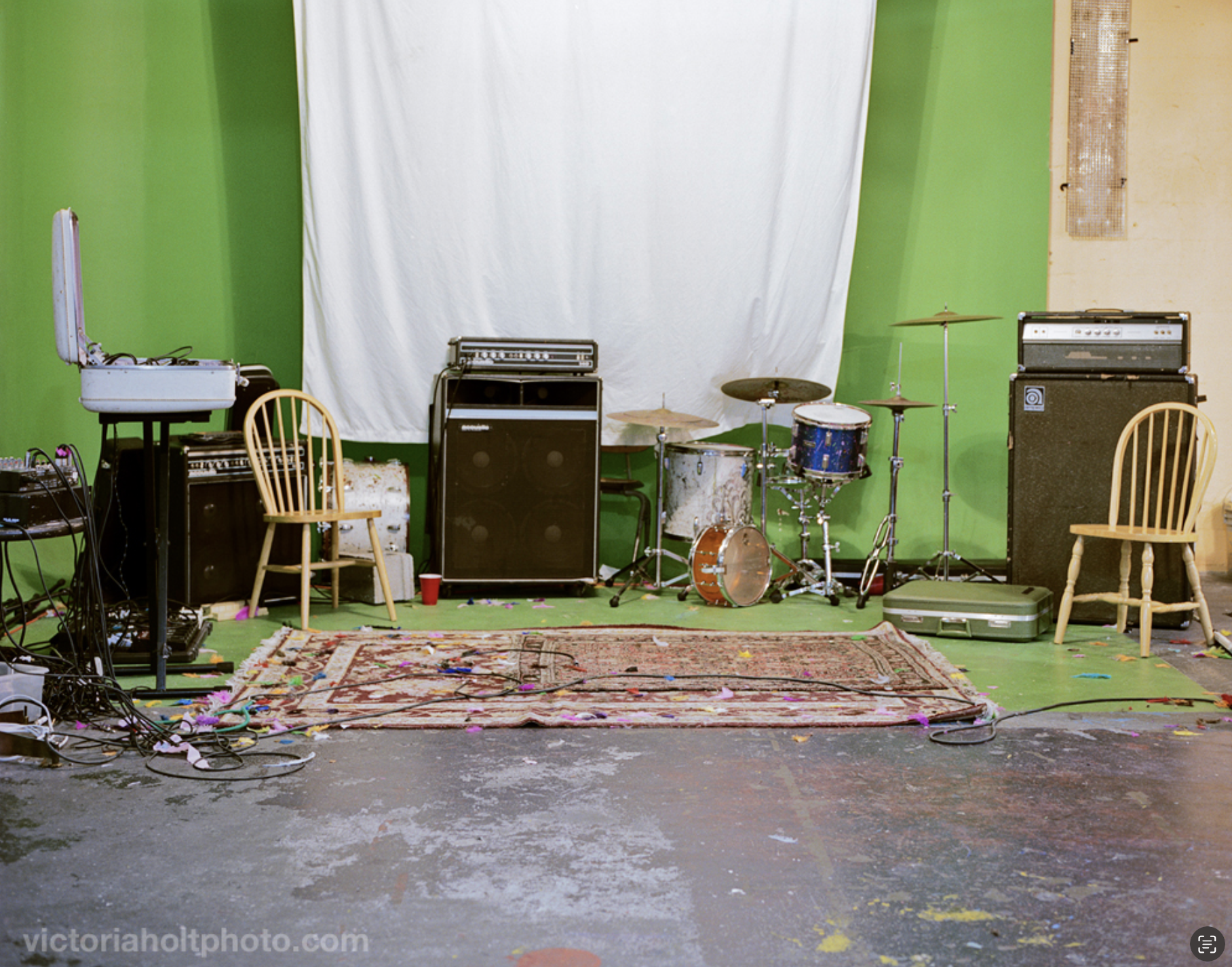 Bright green room with a rug, amps, drum set, and  chairs. Healthy Times Fun Club was a DIY punk house venue on Capitol Hill in Seattle. Photo by Victoria Holt, 2011.